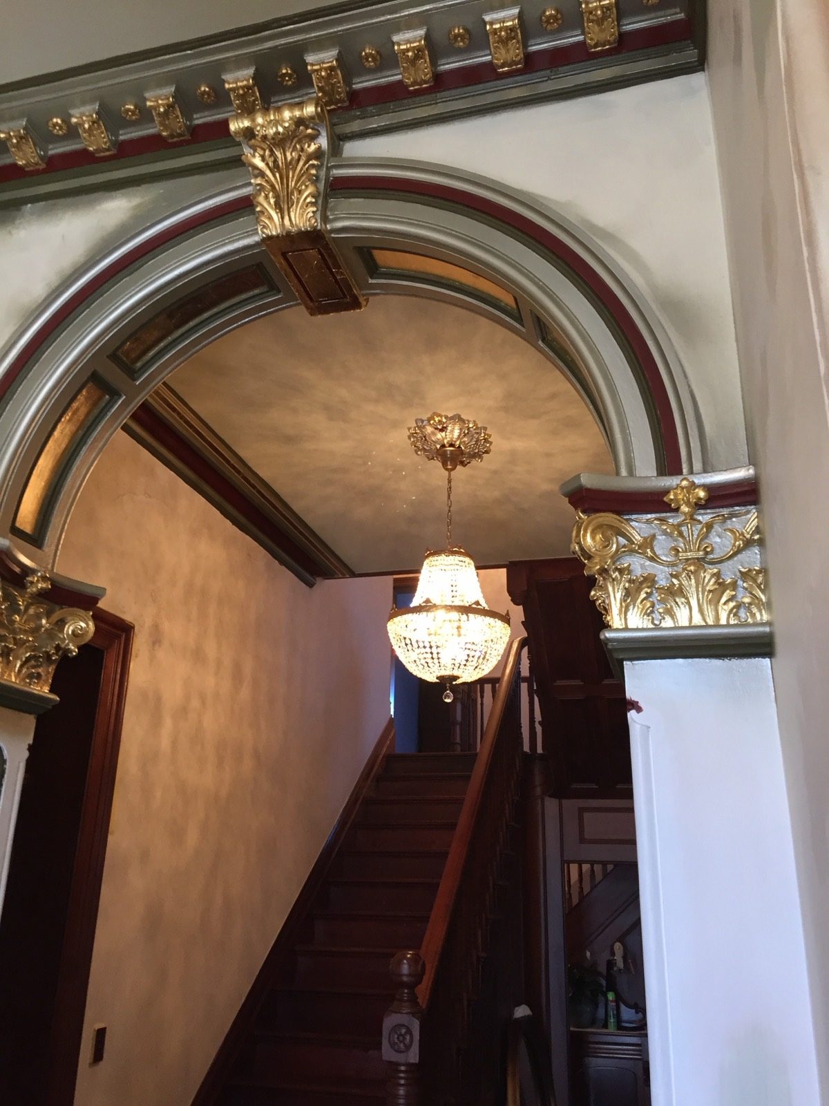 A restored heritage entry archway with gilded detail and timber staircase